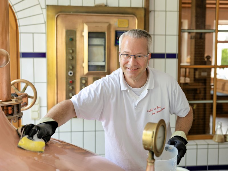 Braumeister Friedrich N. Schulte am kupfernen Sudkessel, den er gerade reinigt